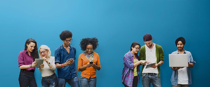 7 junge Menschen stehen nebeneinander und schauen gemeinsame auf Smartphones oder Tablets