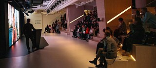 Präsentation in einem großen Raum mit vielen Menschen